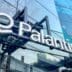 The Palantir corporate logo and name, in white 3D letters, displayed on the glass facade of a modern building.