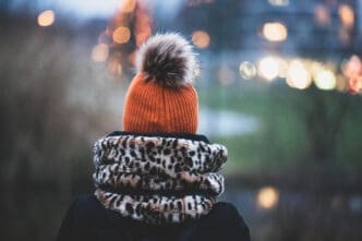 Rear view of a person in an orange pom-pom hat and leopard-print scarf.