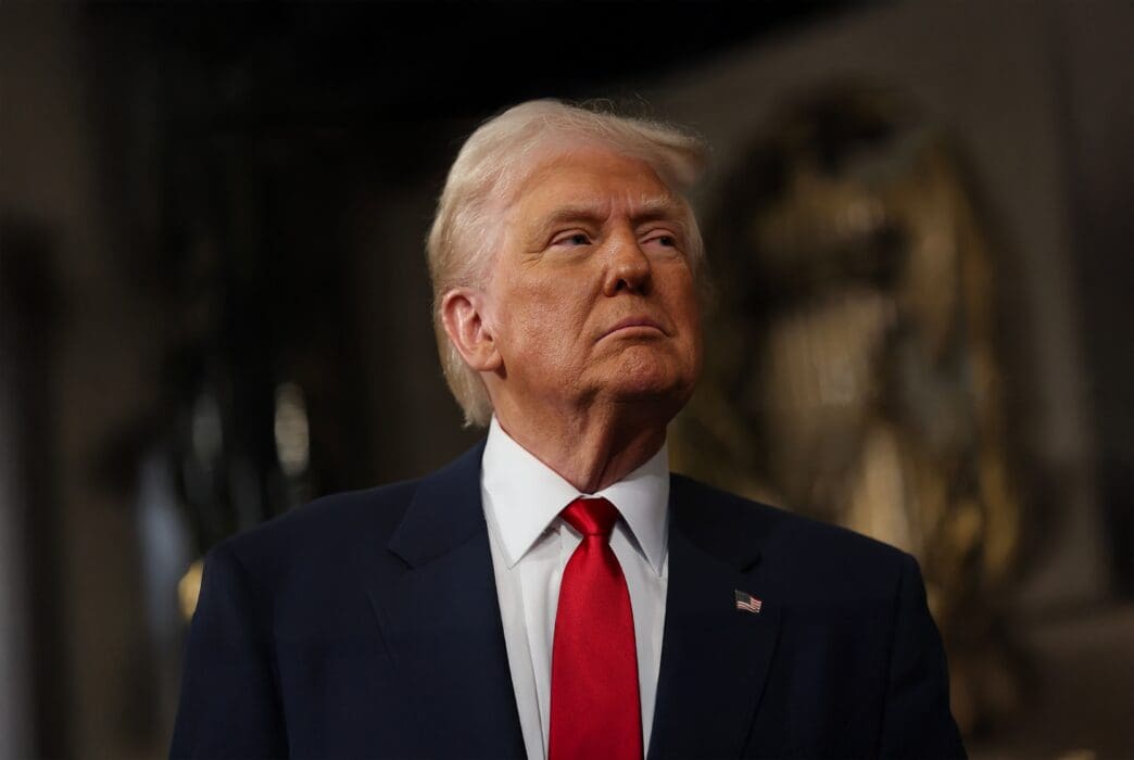Donald Trump in a dark suit and bright red tie looks upward during a formal address at the US Capitol building