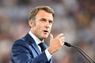French President Emmanuel Macron speaks into a microphone, gesturing with his hand, at the Rugby World Cup 2023 in Paris.