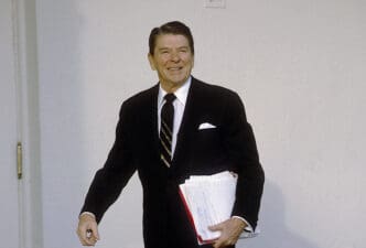 President Ronald Reagan smiling and holding papers in Washington DC on January 30, 1984.
