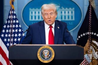 President Donald Trump addresses the press from a podium at the White House briefing room, flanked by U.S. and Presidential flags.