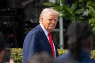 President Donald Trump looks over his shoulder while walking on the White House grounds for an event.