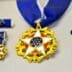 Display case holding the Presidential Medal of Freedom, a gold star with a white and blue center, shown with its ribbon and miniature versions.