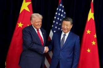 President Donald Trump and President Xi Jinping shake hands in front of the US and Chinese flags.