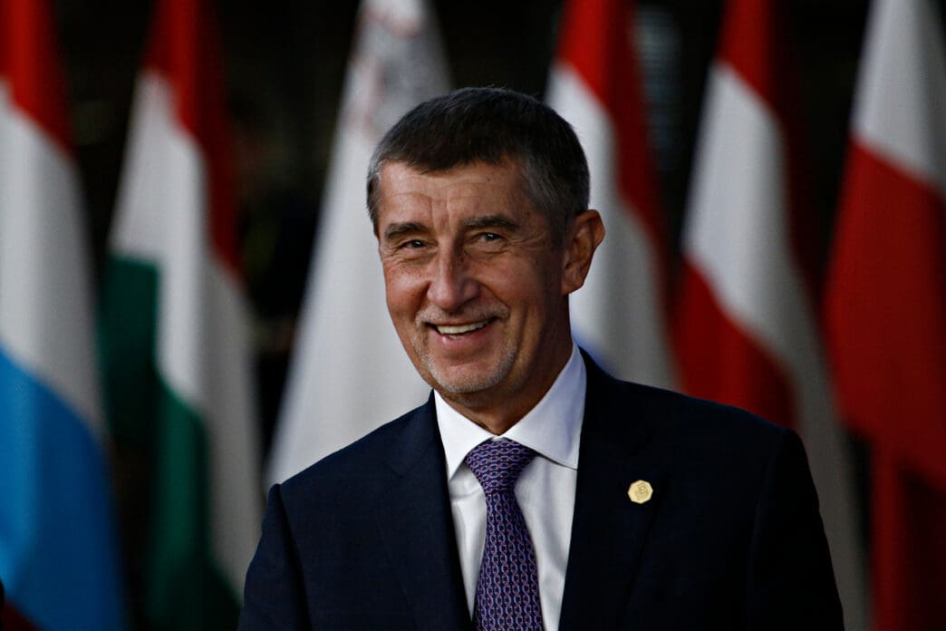 Prime Minister Andrej Babis smiles in front of several national flags