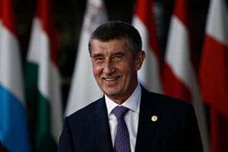 Prime Minister Andrej Babis smiles in front of several national flags