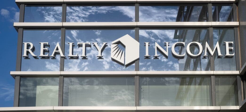 The "Realty Income" logo on the glass facade of a modern office building.