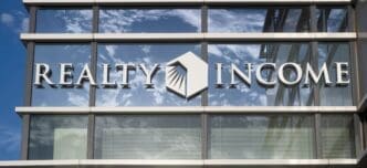 The "Realty Income" logo on the glass facade of a modern office building.