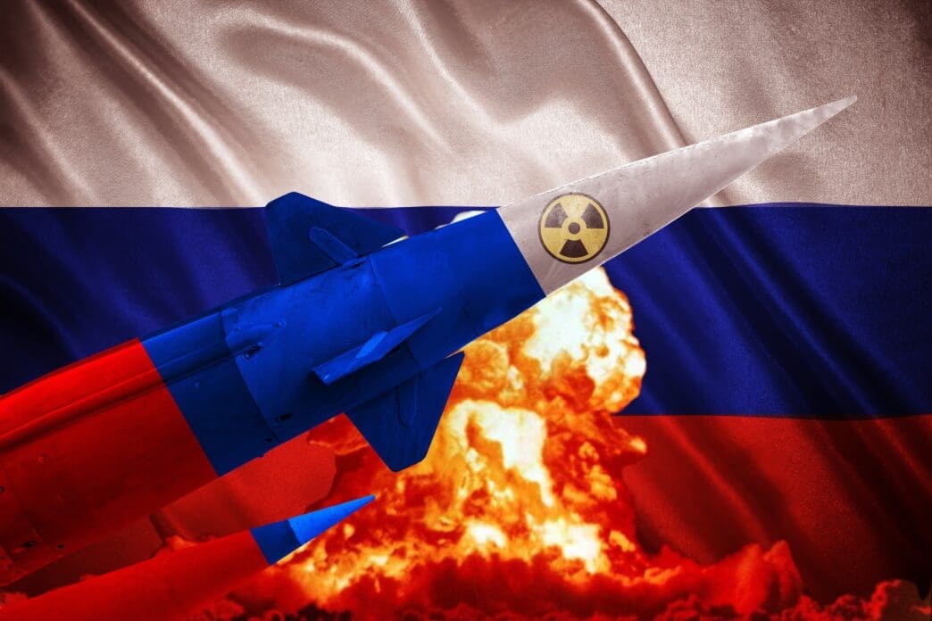 A nuclear missile painted in Russian colors flies in front of a Russian flag and a mushroom cloud.