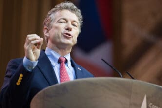 Senator Rand Paul passionately speaks at a podium, gesturing with his right hand.