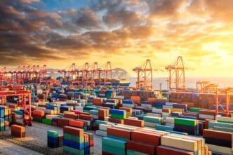 A bustling container port in Shanghai, China, with stacks of colorful cargo containers and large cranes under a dramatic sunset sky.