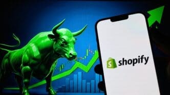 Shopify logo on a smartphone screen, with a green bull and a rising stock chart in the background.