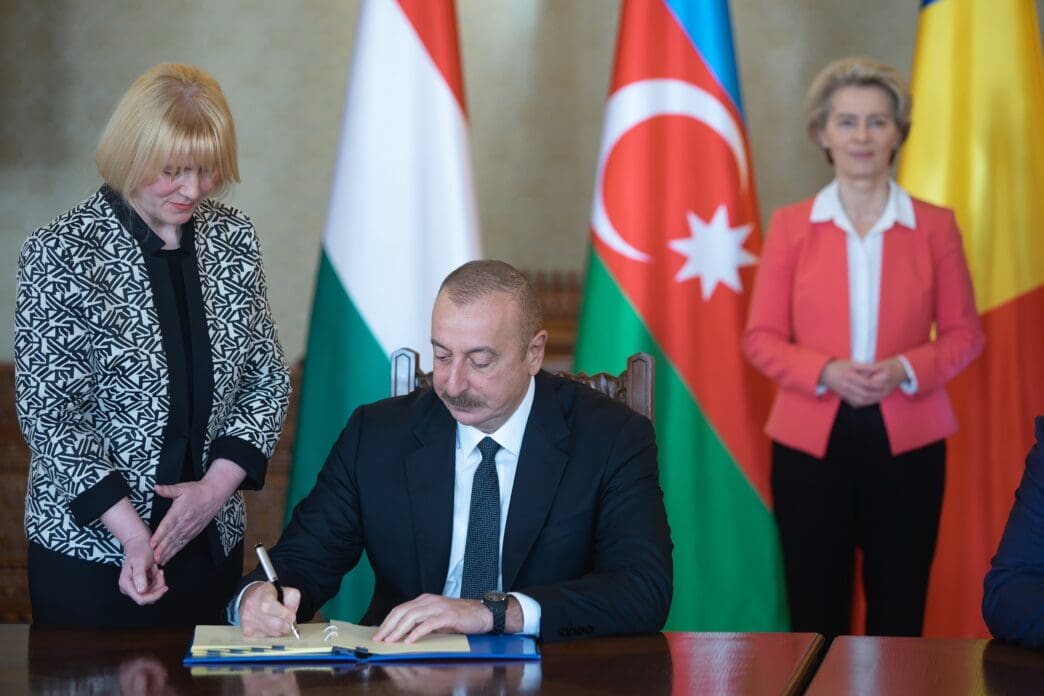 Leaders sign an agreement with national flags in the background