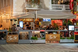 Patrons socialize and eat at the outdoor patio of SoCal Cantina in Miami, illuminated by string lights at night.