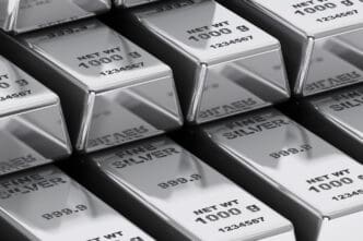 A close-up view of multiple rows of shiny, one-kilogram fine silver bars, neatly stacked and stored.
