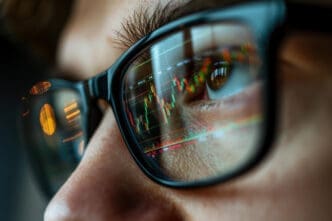 Close-up of a stock market candlestick chart reflecting in a person's eyeglasses.