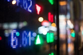 Close-up of a colorful LED stock market ticker showing price changes at night.