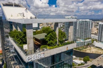An aerial view of the Sugar rooftop bar at the EAST Miami hotel, showing its lush garden setting above the Brickell skyline.