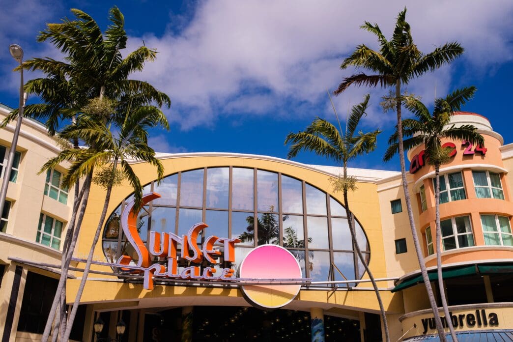 The colorful entrance to the Sunset Place shopping mall in South Miami, Florida, framed by palm trees.