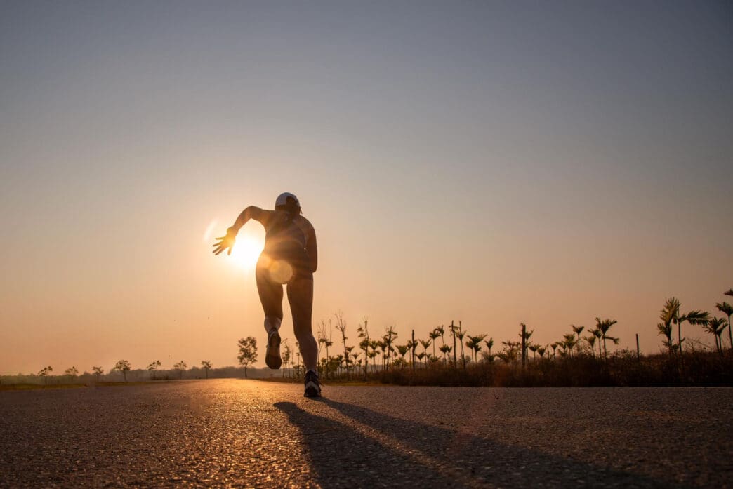 Silhouette of a runner on a road at sunset, with the sun at their back