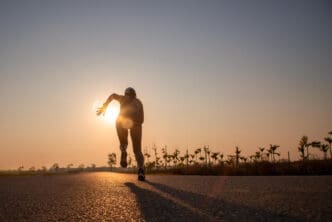 Silhouette of a runner on a road at sunset, with the sun at their back