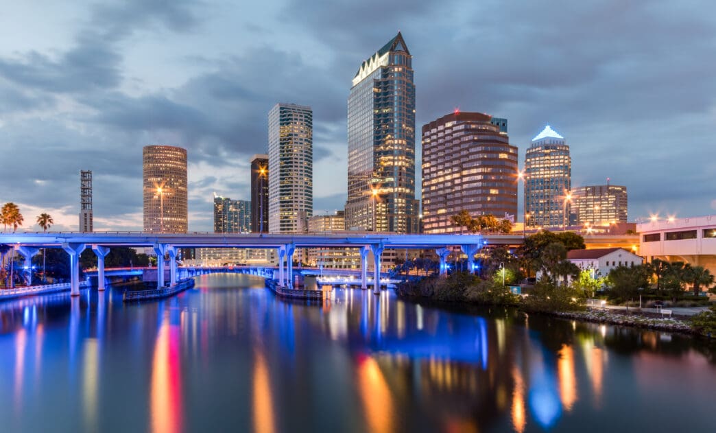 Tampa skyline at dusk with a bridge and water reflecting city lights