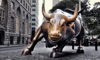 The iconic bronze "Charging Bull" statue stands on a cobblestone street in New York City's financial district.