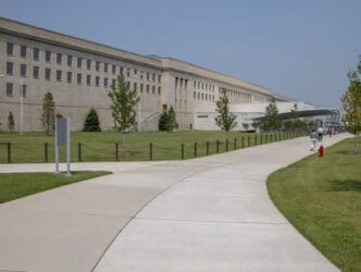 A photo of the Pentagon building in Washington, DC, with a long sidewalk and people walking.
