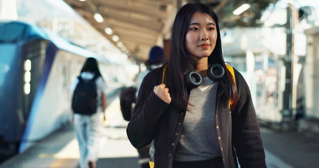 Young Asian woman with headphones walks on a train platform in China