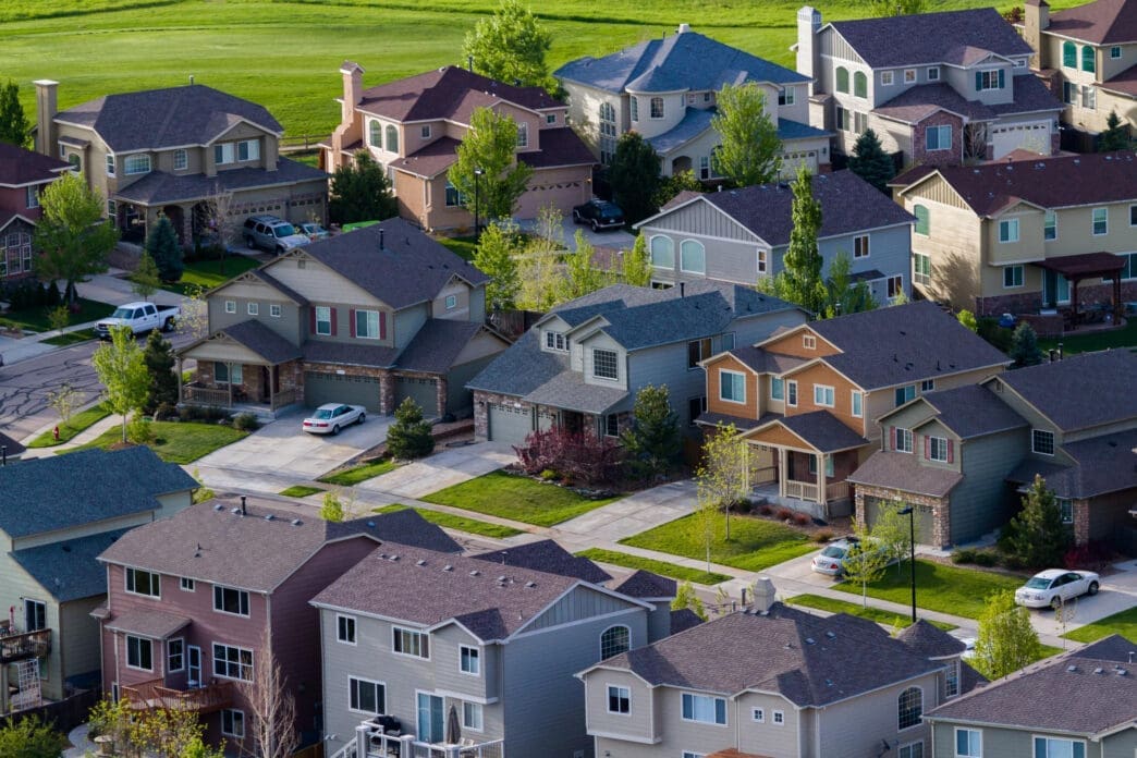Aerial close-up view of a dense, modern suburban housing development with varied house colors.