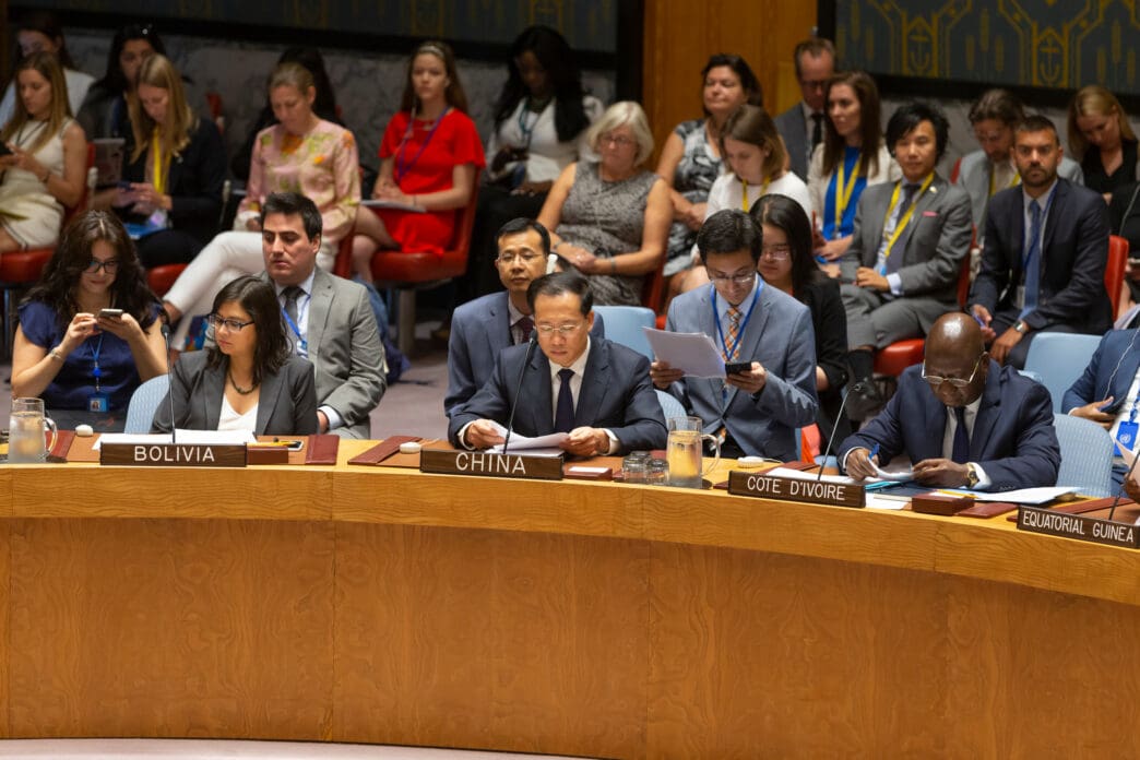 Diplomats from several nations seated at the Security Council table with an audience gathered behind them at the UN.