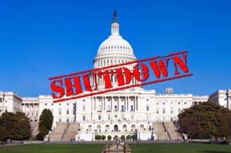 The US Capitol building under a clear blue sky with a red "SHUTDOWN" stamp