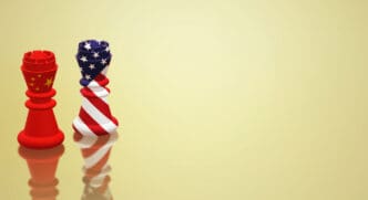 Two stylized chess pieces—one red with the Chinese flag and one striped with the US flag—standing on a reflective golden surface.