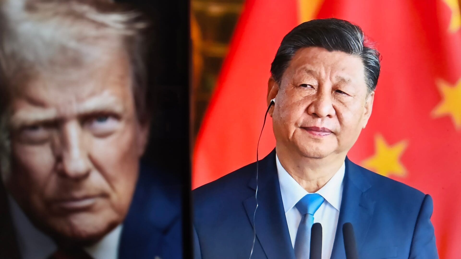 Chinese President Xi Jinping stands in front of the Chinese flag next to a screen displaying a portrait of President Donald Trump.