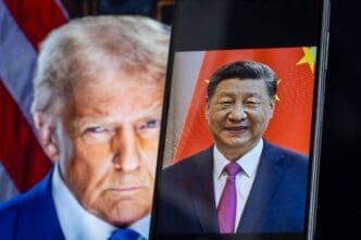 Smartphone shows Xi Jinping's portrait in front of a computer screen showing Donald Trump.