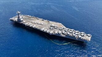 Aerial drone photo of the USS Gerald R. Ford aircraft carrier at sea with planes on deck.