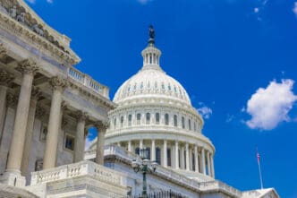 Close-up of the U.S. Capitol Building dome and columns against a bright blue sky with clouds