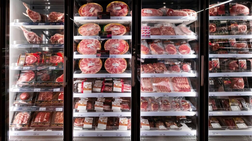 A supermarket refrigerator case fully stocked with various packaged fresh meats.