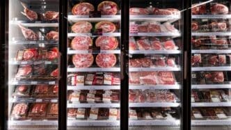 A supermarket refrigerator case fully stocked with various packaged fresh meats.