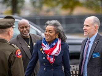 Lieutenant Governor Winsome Earle-Sears, wearing a patriotic scarf, converses with military personnel and a director at the Virginia War Memorial.