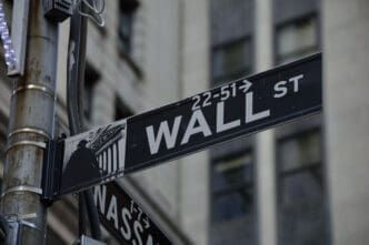 A close-up shot of the black "WALL ST" street sign in New York City.