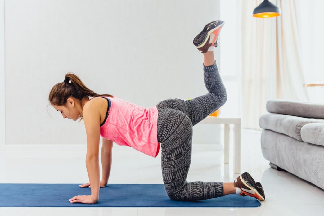 Woman doing donkey kicks on a yoga mat