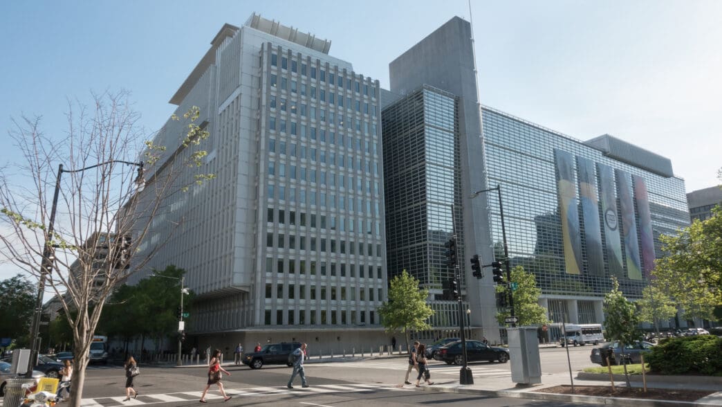 The World Bank Headquarters complex in Washington DC with banners reading "End Poverty" on the glass facade.