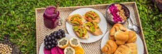 Breakfast tray with fruit buns, avocado sandwiches, and a smoothie bowl.