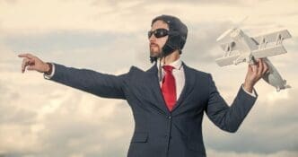 A businessman in a suit and pilot hat launches a toy airplane.