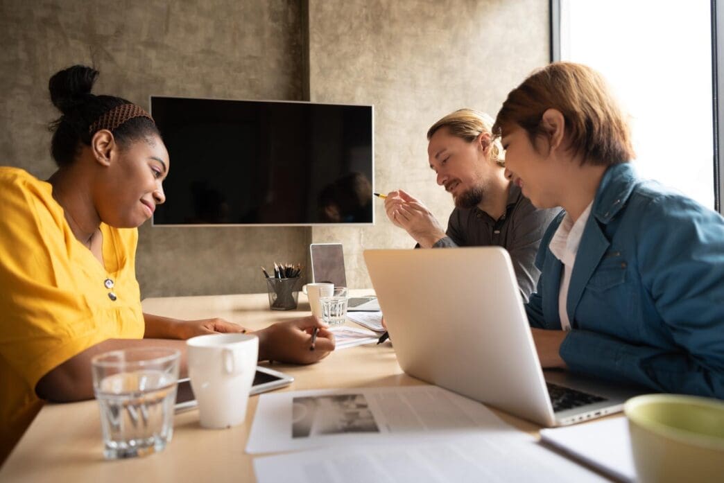 Business people collaborate around a table in a modern office setting.