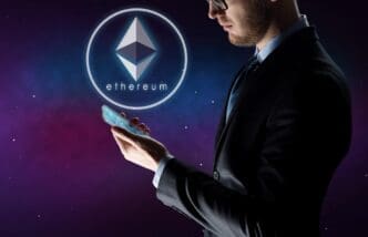 A businessman holds a smartphone, with an Ethereum hologram projected in front of him.