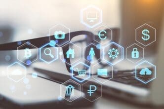 Close-up of a laptop, eyeglasses, and smartphone on a desk with a holographic digital dashboard of business icons.