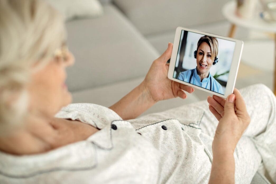 Senior woman in a close-up shot uses a digital tablet to talk to her doctor.